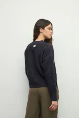 Sweater de punto con textura en relieve, cuello redondo y mangas largas con puños ajustados.