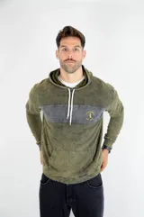 Hoodie de algodón con efecto lavado en color verde oliva. Presenta una franja horizontal en gris oscuro en el pecho con el logo de la marca bordado en amarillo, capucha con cordones ajustables y bolsillo tipo canguro.