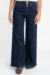 Jean de corte wide leg y tiro medio, confeccionado en denim de algodón. Presenta costuras verticales decorativas a lo largo de las piernas y cierre frontal con botón y cremallera.