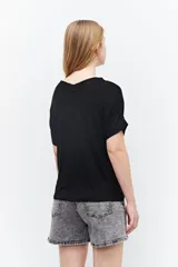Remera marrón de tejido liso, con escote en V, mangas cortas y cierre frontal con botones.