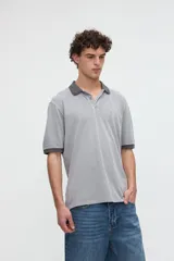 Remera polo de manga corta color rojo con efecto lavado, cuello y puños en contraste marrón. Cuenta con media cartera de botones, aberturas laterales en el dobladillo y un bordado pequeño de una estrella en el pecho.