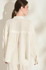 Camisa de lino italiano color beige, de corte holgado, con cuello mao, manga larga y bolsillo aplicado en el pecho.