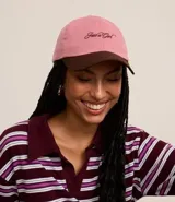 Gorra rosa con visera marrón, confeccionada en sarga de algodón, con bordado frontal con la frase "Just a Girl" en color marrón.