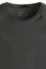 Remera deportiva de hombre, color verde oscuro, de tejido funcional DryMove™ con textura microperforada. Presenta cuello redondo y mangas raglán con costuras planas. Corte ajustado (Muscle Fit).