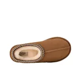 Zuecos UGG modelo Tasman II, confeccionados en gamuza color marrón con forro interno de piel de oveja. Presentan un ribete trenzado decorativo en el cuello y suela de goma resistente.
