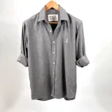 Camisa gris de manga larga con puños enrollados, cuello clásico y cierre con botones.