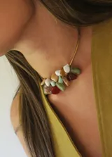 Gargantilla rígida dorada con piedras de colores.