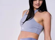 Top deportivo gris con espalda racerback y logo blanco en el lateral.