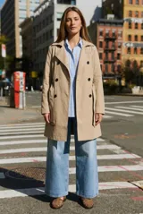 Trench impermeable de corte oversize en color camel, con diseño de doble botonadura, solapas clásicas y cinturón ajustable en la cintura.