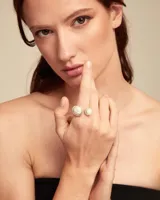 Anillo plateado con dos perlas blancas, una grande y otra pequeña.