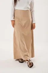 Falda larga color beige confeccionada en tela suave con acabado tipo piel de durazno y cierre invisible lateral.