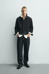 Sobrecamisa de corte regular fit color negro con pespuntes en contraste blancos. Presenta cuello solapa, mangas largas con puños abotonados, bolsillos frontales de vivo y cierre de cremallera oculta por solapa con botones.