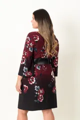 Vestido corto en jersey estampado color bordó con flores rojas y grises, de corte suelto con mangas 3/4 acampanadas y cuello redondo. Incluye cinturón ancho de cuero sintético negro con hebilla circular. 