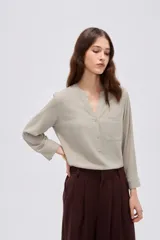 Blusa de viscosa color beige con cuello en V, cierre parcial de botones frontales, bolsillo en el pecho y mangas 3/4.