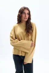 Buzo de tejido de punto color mostaza, de corte holgado, con cuello redondo acanalado y mangas anchas tipo campana.