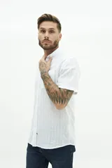 Camisa de manga corta confeccionada en lino y algodón, con fit regular y logo bordado. Color beige con rayas verticales blancas.