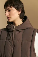 Chaleco acolchado de nylon color negro, con diseño capitoneado, capucha integrada y cierre frontal con tirador metálico.
