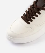 Championes de caña baja en PU color blanco, con recortes contrastantes en marrón y cordones al tono. Cuentan con suela robusta y diseño urbano.