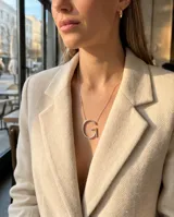 Collar de cadena fina con dije de letra inicial mayúscula de gran tamaño, disponible en acero plateado o con baño de oro.