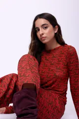 Top de manga larga confeccionado en microtul doble con diseño estampado gráfico en tonos marrón y rojo. Presenta un ajuste al cuerpo y escote redondo.