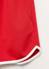 Short deportivo de corte recto, color rojo con ribetes blancos en contraste en los bordes inferiores. Cuenta con cintura elástica y bolsillos laterales.
