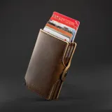 Billetera compacta de cuero sintético color marrón con doble compartimento de aluminio para tarjetas y bolsillo exterior con cierre metálico.