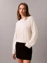 Sweater Calvin Klein de punto color blanco, de corte regular y manga larga, con cuello redondo y el logo de la marca en relieve en el pecho. Cuenta con puños y dobladillo acanalados.