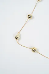 Collar largo de cadena fina plateada con dijes esféricos y orgánicos distribuidos a lo largo de la pieza.