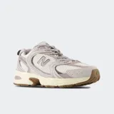 Championes New Balance modelo 530, de estilo retro, en color gris claro con detalles blancos y suela marrón. Combinan malla transpirable y refuerzos sintéticos con tecnología de amortiguación ABZORB.