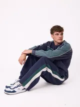 Pantalón tipo babucha de la marca Rusty, color azul petróleo con franjas laterales en color bordó. Presenta cintura elástica con cordón ajustable y logo bordado en la pierna izquierda.