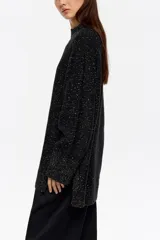 Sweater de punto negro con efecto tweed o neps en color dorado/amarillo claro, cuello alto tipo caja y mangas largas. Corte recto y holgado.