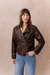 Chaqueta tipo biker de cuero sintético color marrón, con cierre frontal asimétrico, cuello con solapas y broches metálicos, y bolsillos laterales con cierre.