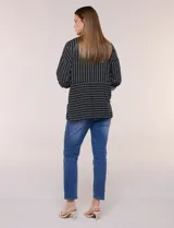 Camisa de rayón negra con patrón de líneas blancas. Presenta cuello camisero, cierre frontal con botones, mangas largas con puños vueltos y un diseño con corte horizontal que alterna líneas verticales en la parte superior y horizontales en la inferior.