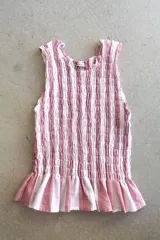 Top de lino a rayas azules y blancas, sin mangas, con diseño fruncido tipo nido de abeja en el torso y doble volante en el bajo.