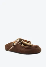 Zueco de gamuza marrón, estilo slip-on, con cordones frontales decorativos, abalorios y suela plana.
