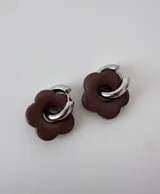 Aros de acero quirúrgico con argolla plateada y dije de flor translúcida en color lila con lunares negros.