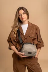 Bandolera pequeña de diseño moderno, confeccionada en tafeta liviana y resistente. Cuenta con cierre superior, correa ancha ajustable y logo frontal de la marca.