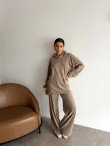 Conjunto de dos piezas compuesto por un buzo con capucha de corte holgado y mangas largas, y un pantalón de corte recto y tiro alto. Ambas prendas son de color marrón liso.