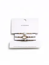 Set de tres pulseras elásticas con cuentas de diferentes materiales y diseños: una con cuentas blancas y doradas, otra con cuentas doradas y un dije ovalado, y la última con cuentas facetadas grises y negras.