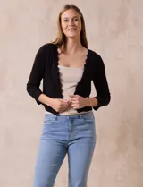 Cardigan tejido en hilado fino color blanco, marca Cable & Gauge. Abertura central con broche interno y terminación ondulada.