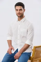 Camisa de lino de manga larga en color beige, con cuello camisero, cierre frontal de botones y un bolsillo ojal en el pecho.