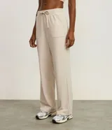 Pantalón deportivo de corte recto confeccionado en microfibra color beige. Presenta cintura elástica con lazo ajustable y bolsillos laterales.