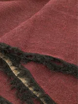 Bufanda de tejido suave y ligero, color bordó con flecos negros y beige en los extremos.