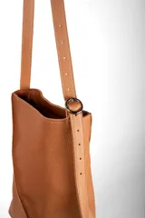 Bolso tipo bucket bag de cuero plena flor negro, con diseño amplio y liviano. Cuenta con cierre metálico, forro de sarga de algodón, bolsillo interior, correa larga ajustable y herrajes metálicos con acabado níquel.