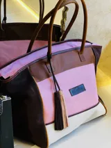 Bolso de fin de semana estilo tote de lona con estampado camuflado, detalles en cuero marrón y gamuza azul, manijas largas y borla decorativa colgante.