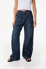 Pantalón jean de corte amplio y relajado, color azul oscuro, con bolsillos traseros grandes y detalles de costuras marcadas.