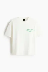 Remera de corte holgado en punto de algodón, con cuello redondo acanalado y hombros caídos. Presenta un estampado frontal con la inscripción Soho NYC Athletics Dept. en color verde.