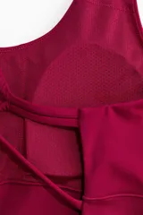Mono corto deportivo de corte ajustado, color fucsia, con escote redondo, breteles finos cruzados en la espalda y soutien integrado con relleno extraíble.