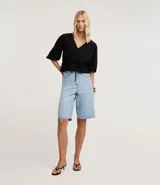 Blusa color vino tinto, con escote cruzado en V, mangas tres cuartos abullonadas con elástico en el puño y peplum ajustado en la cintura con lazo regulable.