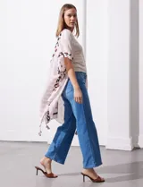 Kimono tejido color beige con estampado abstracto en tonos marrones y negros. Tiene mangas amplias estilo japonés y terminación con borlas en el ruedo.